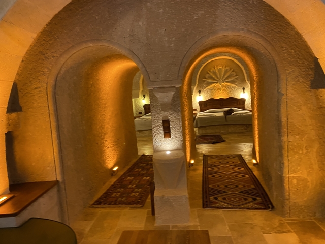       Interior of a cave hotel with beds and lighting.
  