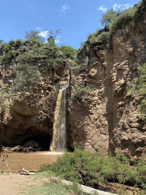       A waterfall cascading over rocky terrain with greenery around.
  