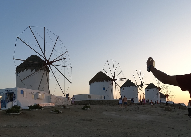 Windmills on a hill with people walking.