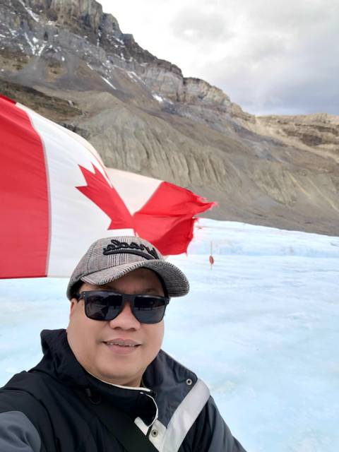 Person holding a Canadian flag with a glacier in the background.