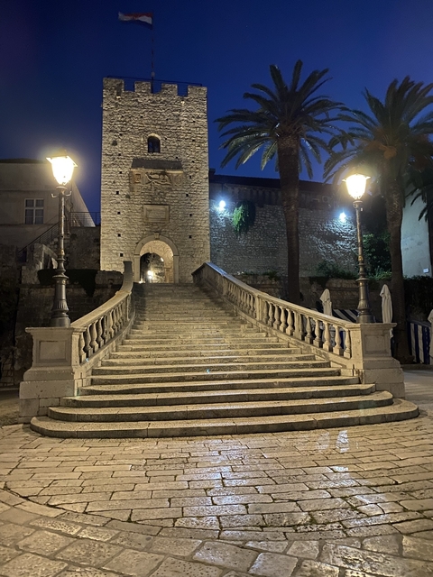       Stairway leading to a historic stone archway, illuminated at dusk.
  