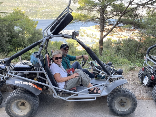 Two people in a dune buggy with seaside view.