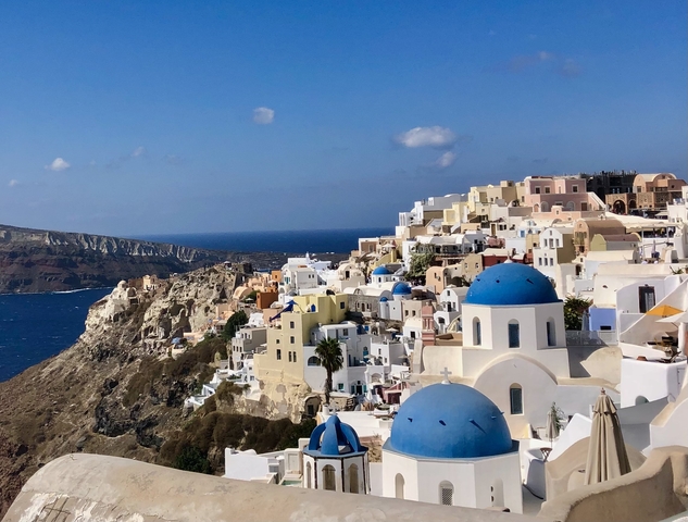 White buildings with blue domes overlooking the Aegean Sea.