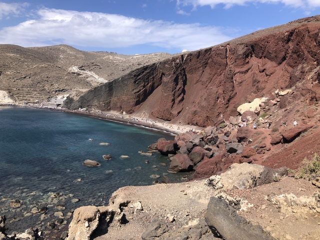 Red and black rock landscape with blue sea.