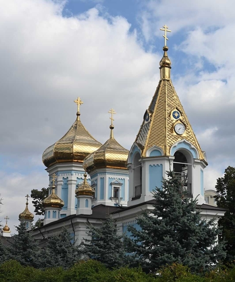       Churches with vibrant domes under blue sky.
  