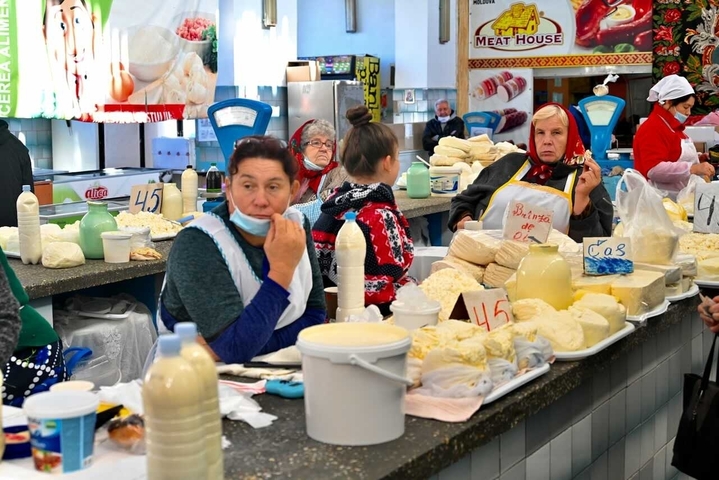       Women selling cheese at an indoor market.
  