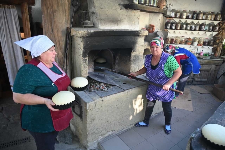       Women baking traditional bread in an outdoor oven.
  