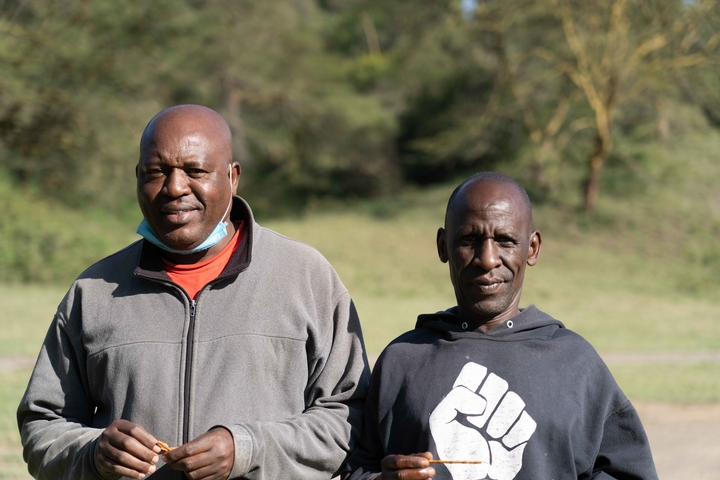 Two people outdoors with trees in background.