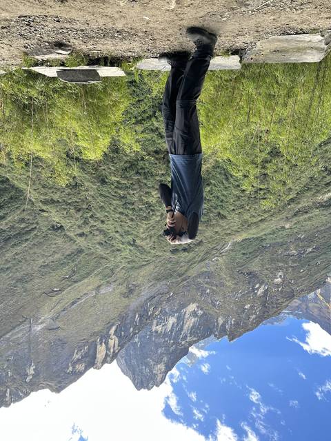       Person taking a photo in a mountainous landscape.
  