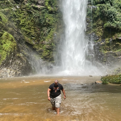       Person standing in front of a large waterfall.
  