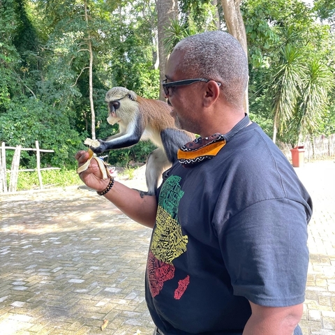       Man interacting with a monkey in a park.
  