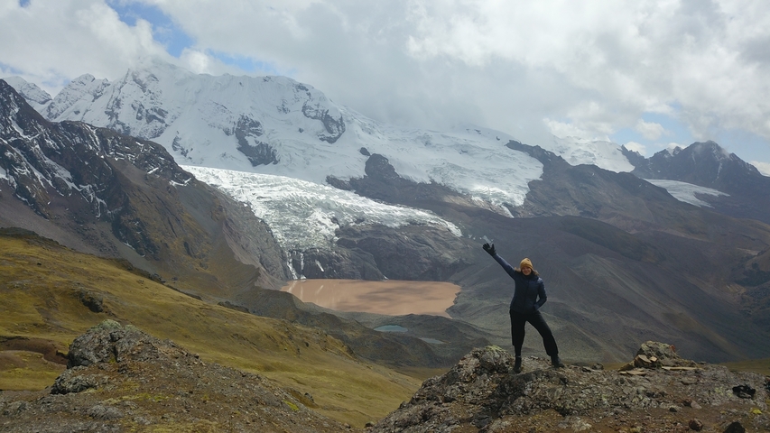 Person posing triumphantly in mountainous landscape.