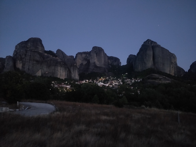Dramatic rock formations with a town at their base at dusk.