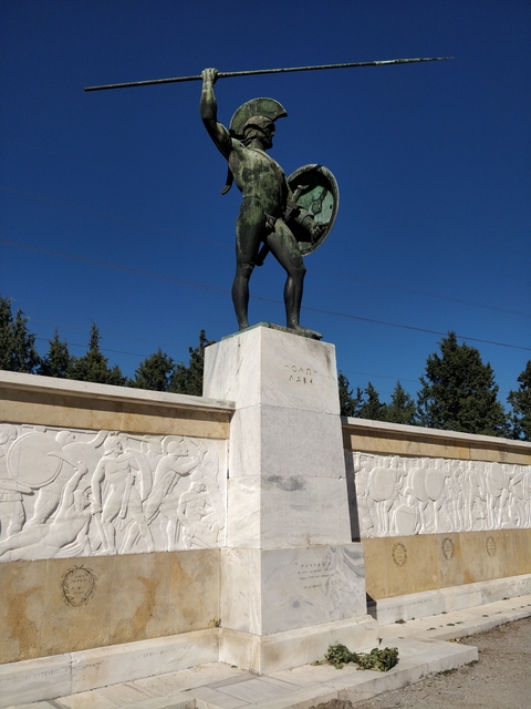 Statue of a warrior on a pedestal with relief carvings.