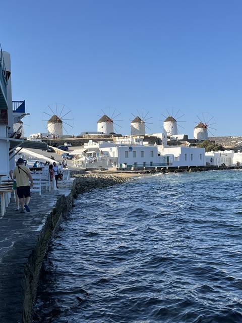       Windmills along the coast with people walking nearby
  