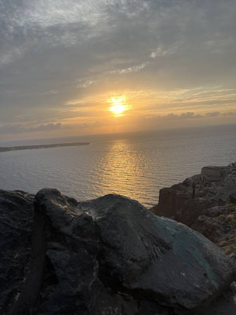       Sunset over the sea with rocks in the foreground
  