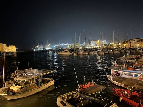       Boats docked at a lit harbor at night
  