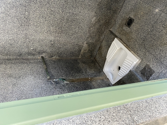 Squat toilet in a tiled room.