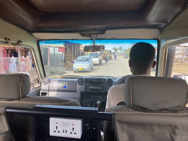       Driver inside a vehicle moving through a town street.
  