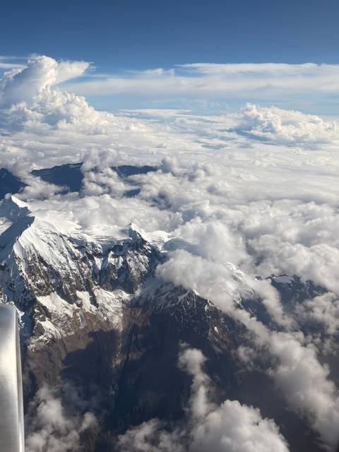 View from an airplane window of clouds and mountains.