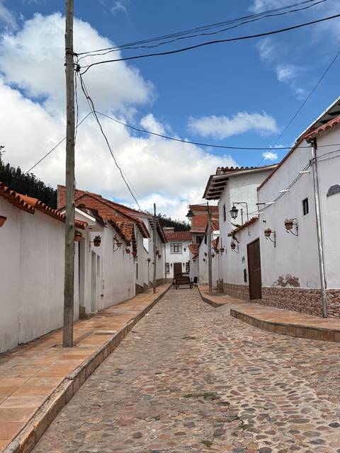 Narrow, cobblestone street with white buildings.