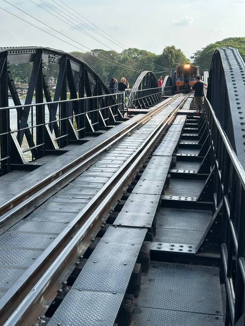       Train on a bridge over a river with mountains in the background.
  