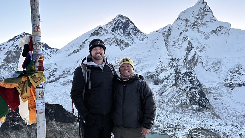       Two people posing with snowy mountains in the background.
  