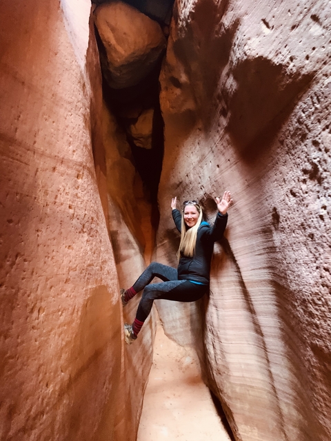 Person playfully posing inside a canyon.