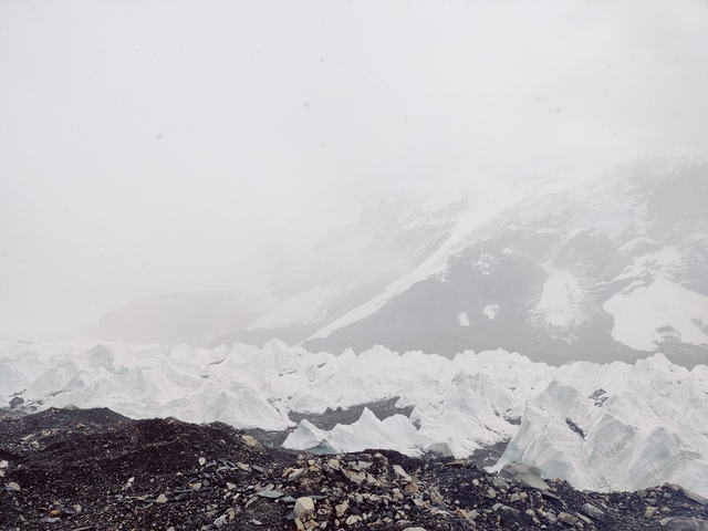 Snow-covered landscape with rugged terrain and mist.