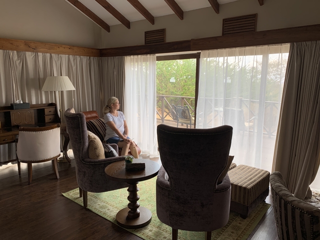       A woman sitting by a large window looking outside.
  