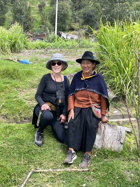       Two people in traditional clothing sitting outdoors.
  