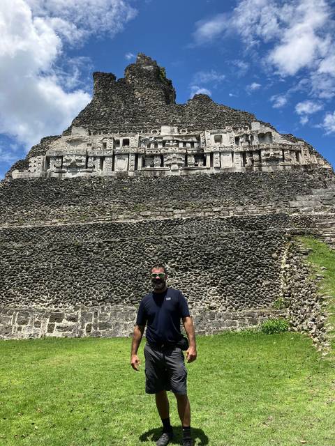       A person posing in front of a stone structure with ancient carvings.
  