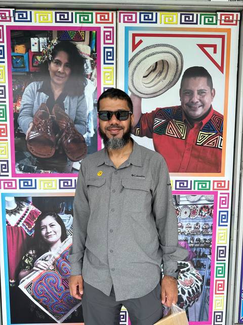       Person in front of colorful portraits and designs on a wall.
  
