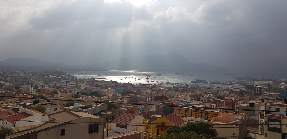 Aerial view of a coastal town with sun rays breaking through clouds.
