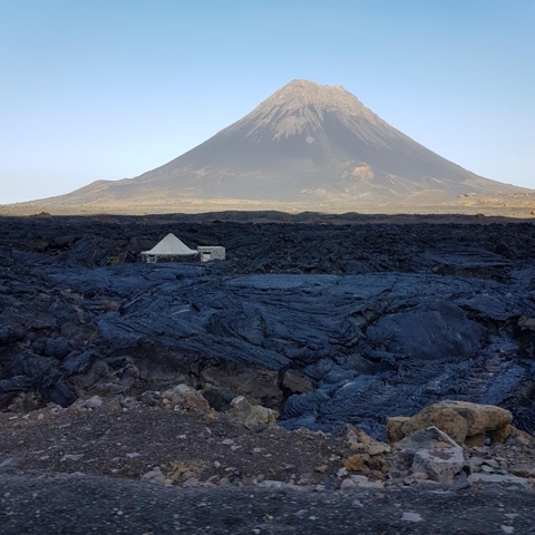 Volcanic landscape with a prominent peak in the background.