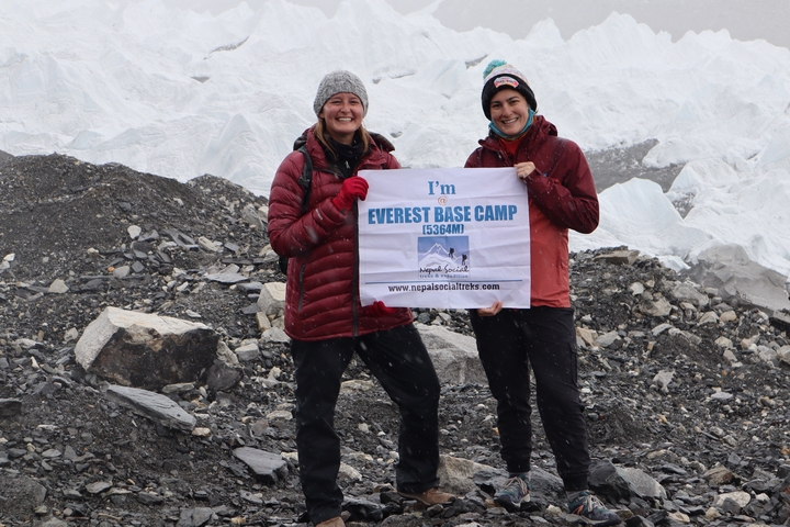 Two people at Everest Base Camp holding a sign.