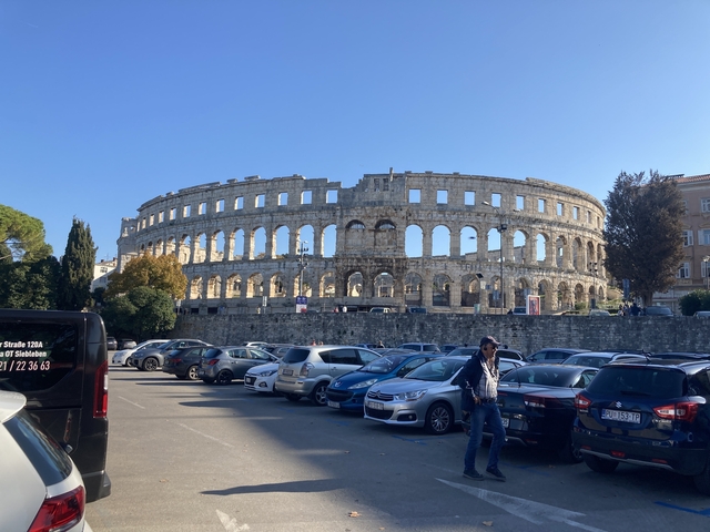       View of a historic amphitheater with people around.
  