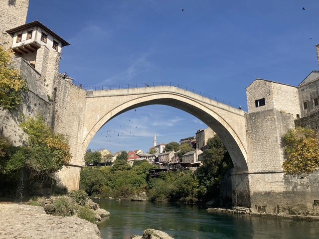 A historic bridge in Mostar with a town in the background.