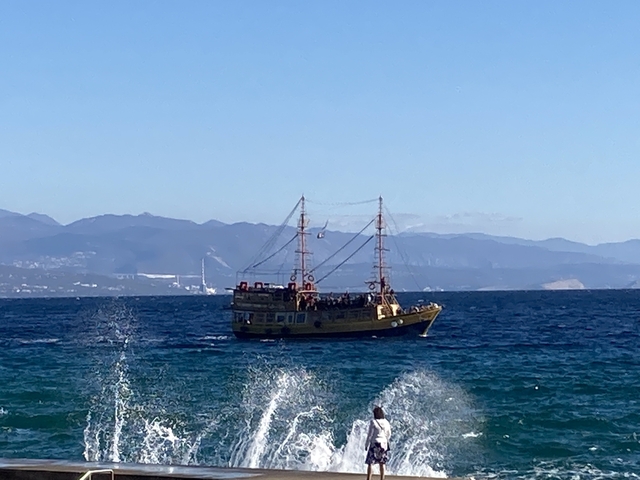 A boat sailing on a calm sea with mountains.