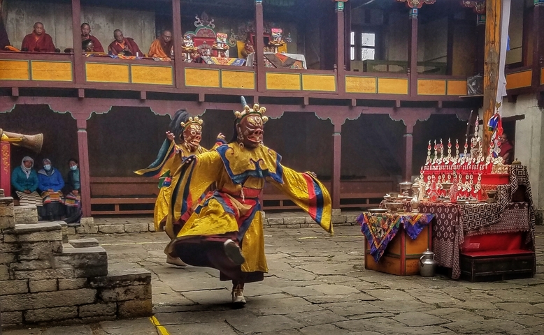 Traditional dance performance with colorful costumes inside a monastery.