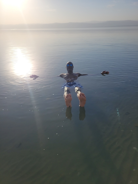 Person floating in the water with sunglasses.