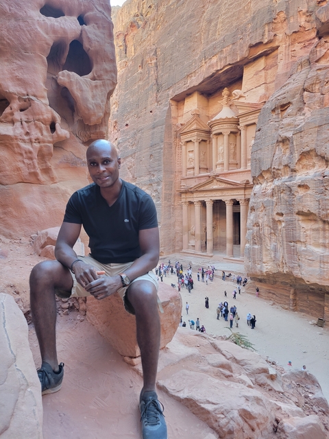 Person sitting in front of the Petra Treasury in Jordan.