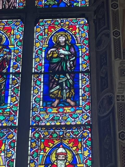       Colorful stained glass window depicting religious figures.
  