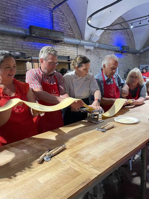       People participating in a pasta making class.
  