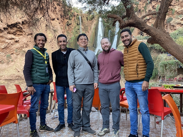 Group of friends posing in front of a waterfall with red rock background.