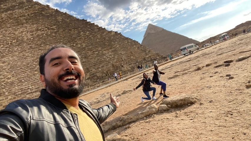       Selfie in front of the pyramids with two people posing.
  