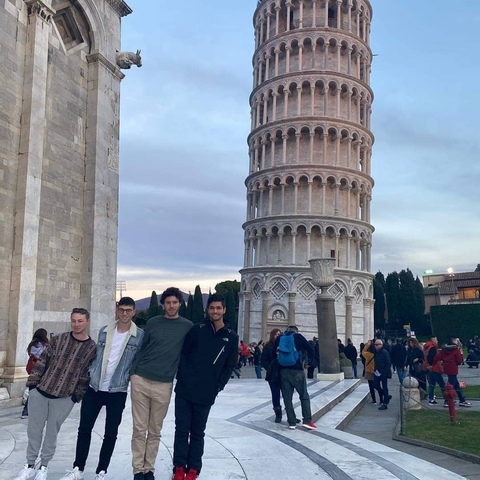 Four people posing in front of the Leaning Tower of Pisa.