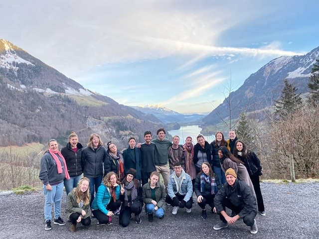 Group of friends posing with a majestic mountain and lake view.