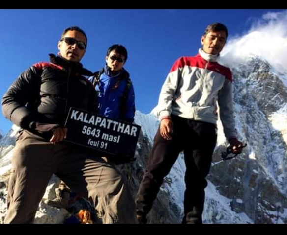       Three men posing with a sign reading 'Kala Patthar.'
  