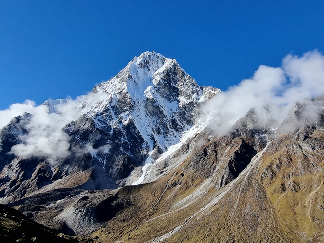       Tall snow-covered mountain under a clear blue sky.
  